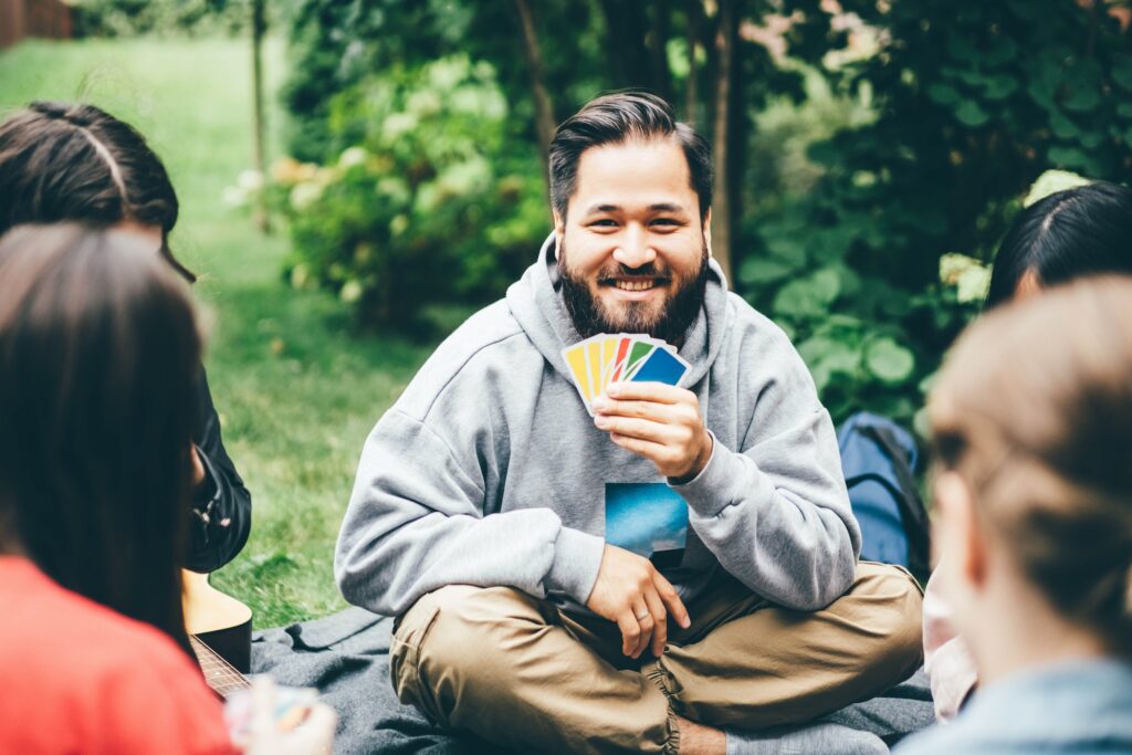 Friend having fun, smiling and playing board games outside.